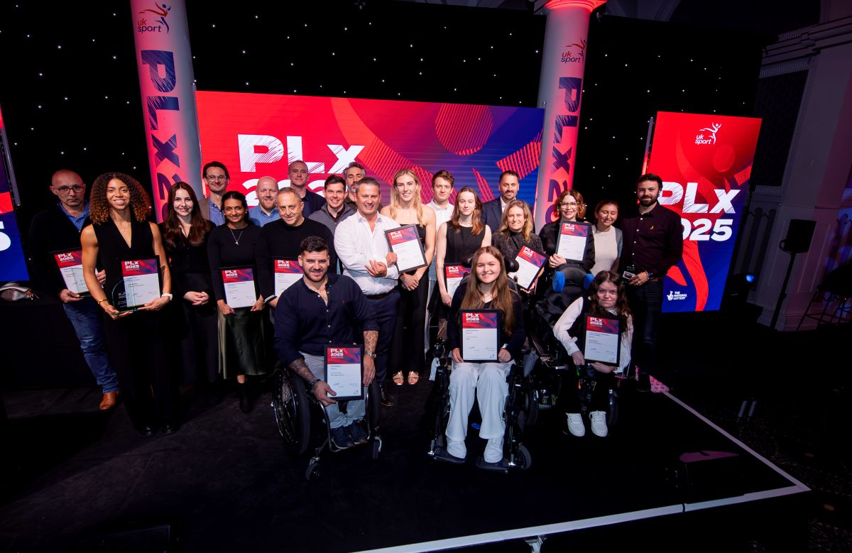 Award winners on stage at the PLX 2025 event, holding certificates in front of vibrant UK Sport branding.