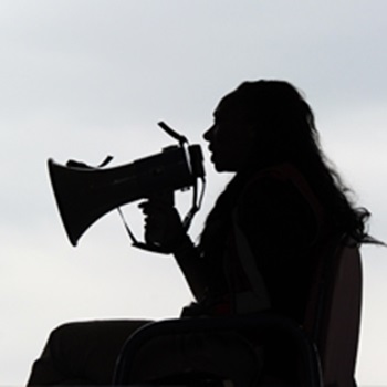 Silhouette of a person with longhair speaking into a megaphone