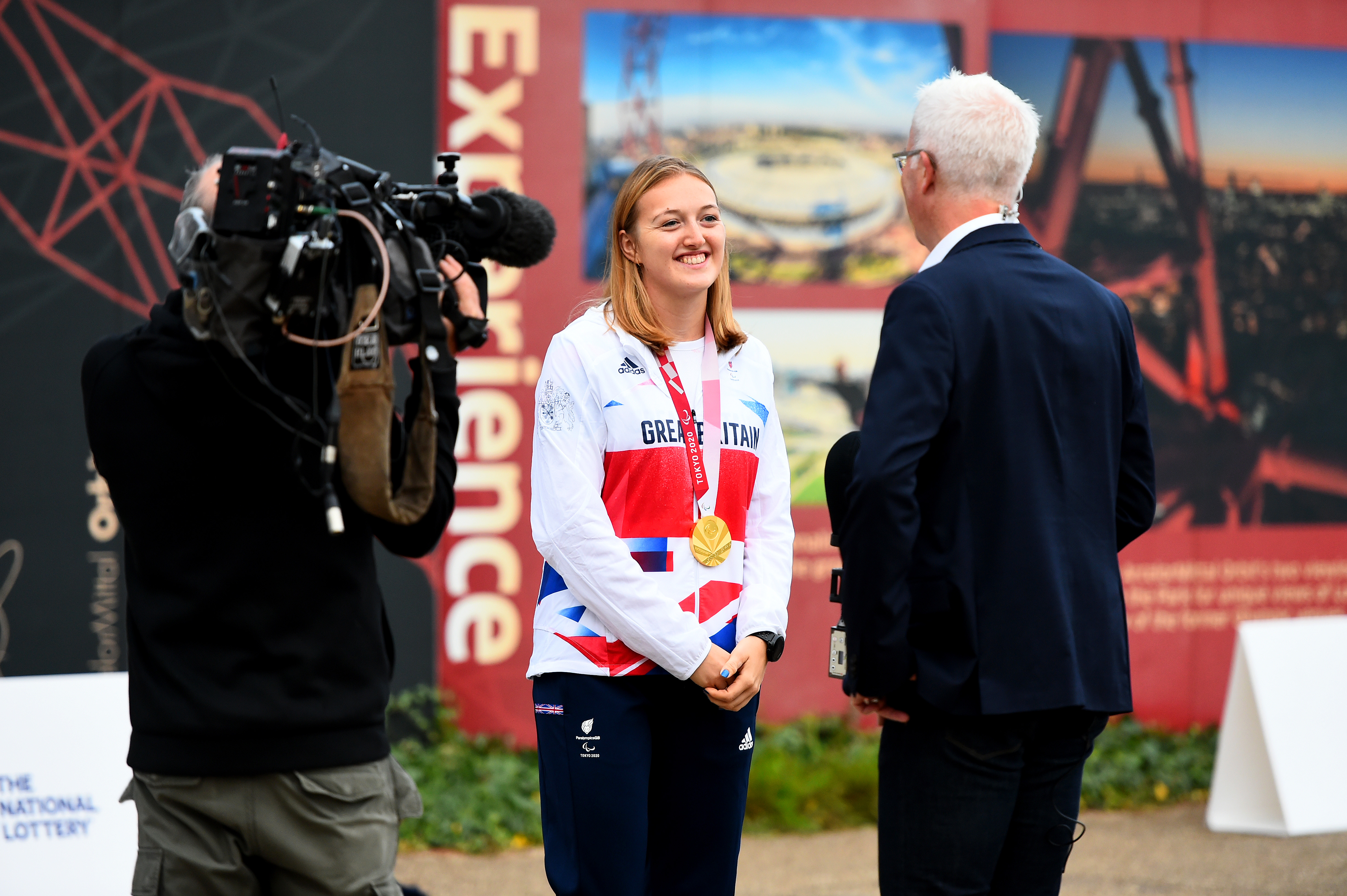 Ellen speaking to a journalist with her medal around her neck