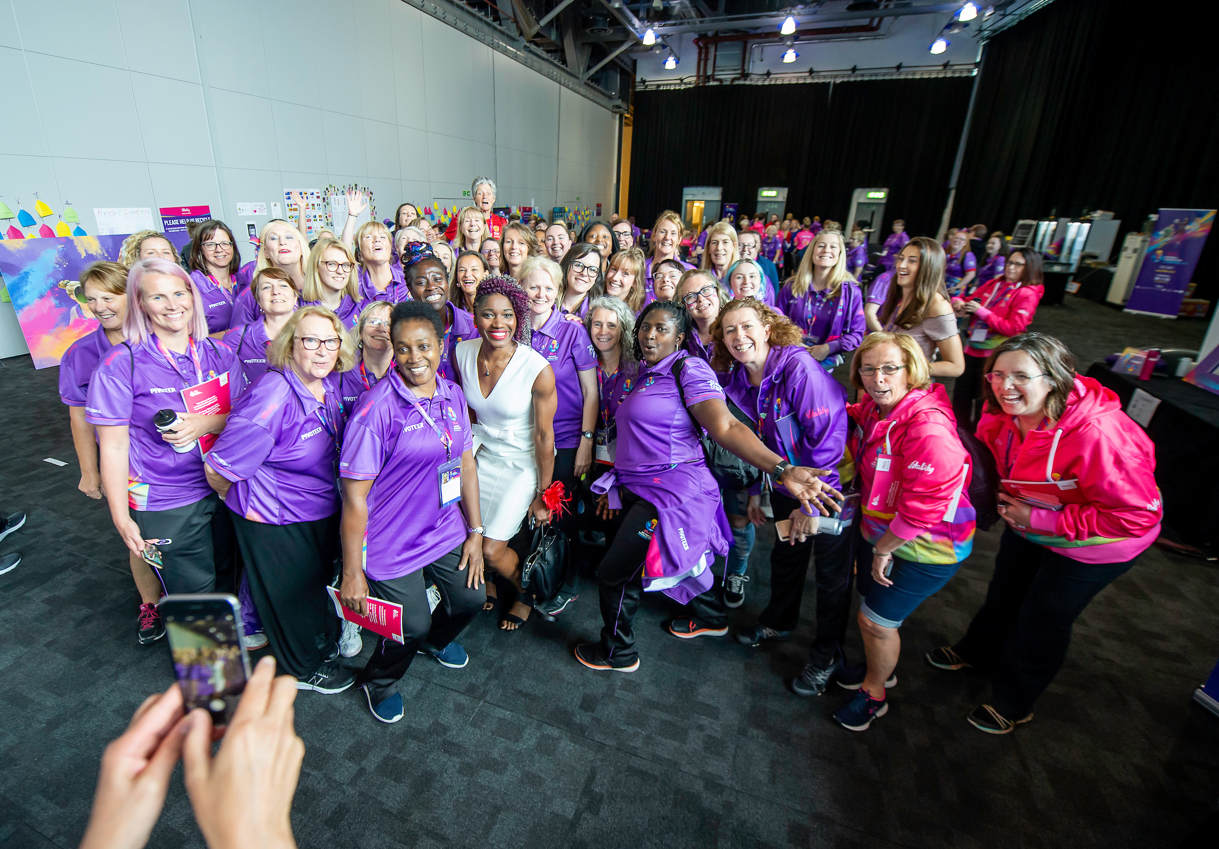 Group of volunteers smiling and laughing for a selfie photo at the Netball World Cup event