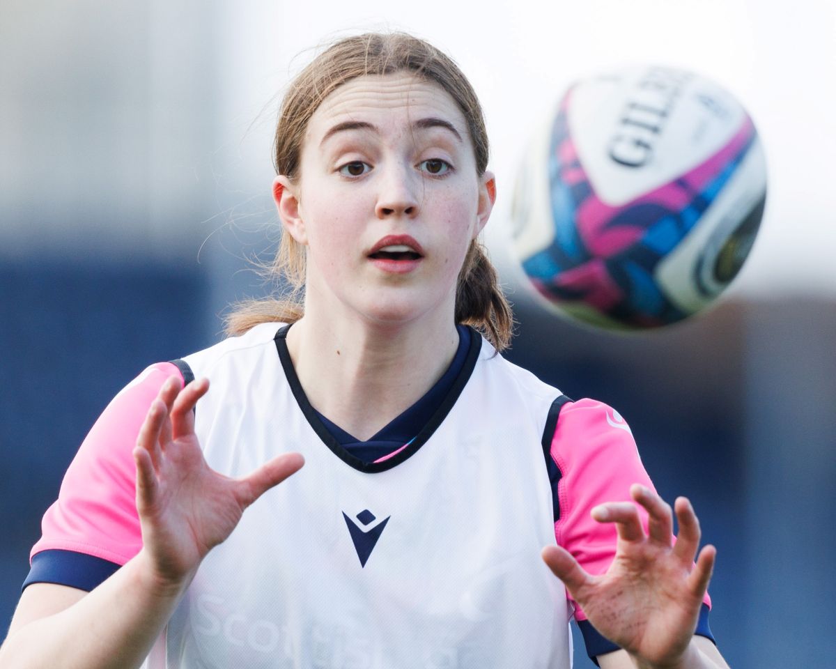 Scotland player Nicole Flynn holds her hands up ready to catch a rugby ball which is flying towards her.
