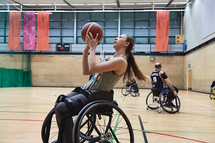 Female wheelchair basketball player lines up a shot at the hoop.