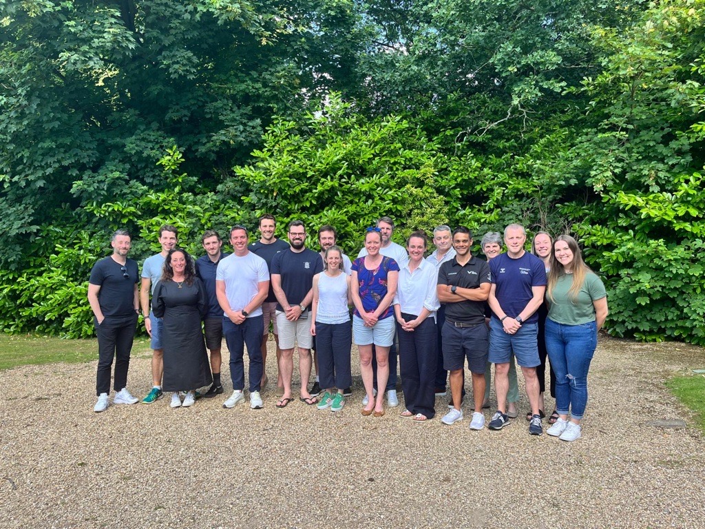 Group of people stood together in front of a cluster of trees