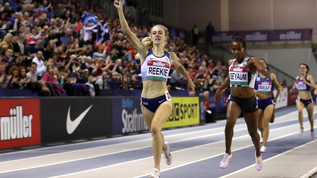 Gemma Reekie crossing the finish line with her hand up in the air on a athletics track