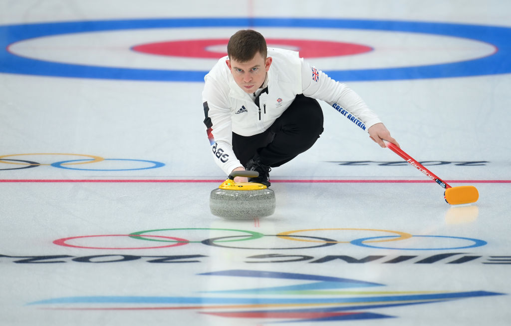 Greg sliding on the ice with a curling stone in hand