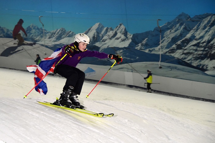 a kid jumping on skis with a Gb flag