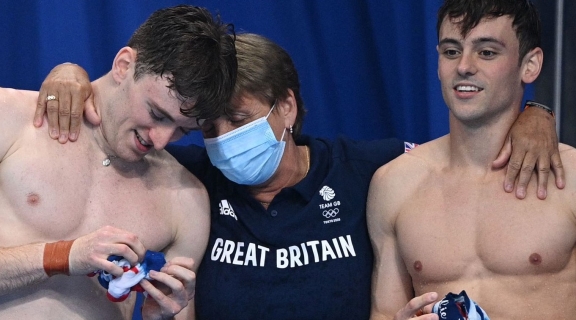 Great Britain high-performance diving coach Jane Figueiredo embracing divers Tom Daly and Matty Lee after dive at Tokyo 2020 Olympics