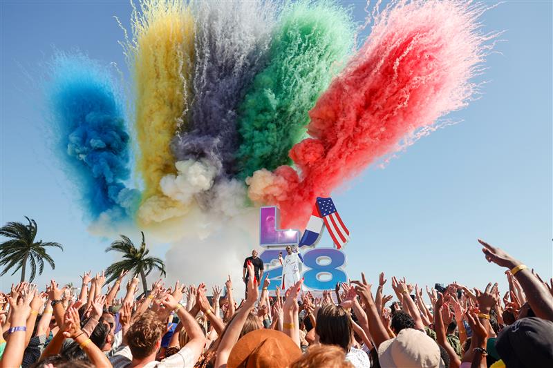 crowds with hands in the air on the beach in front of a big LA 28 sign