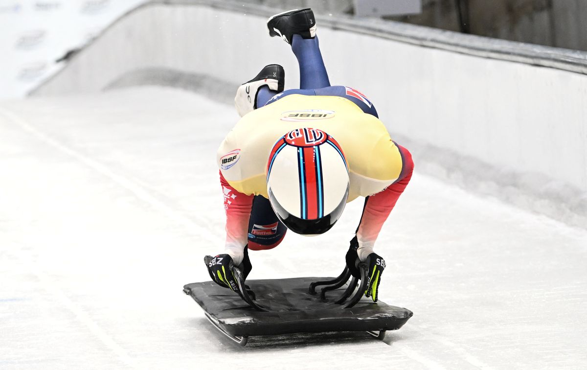Skeleton athlete sprint-starts on ice, diving onto their sled in a racing position.