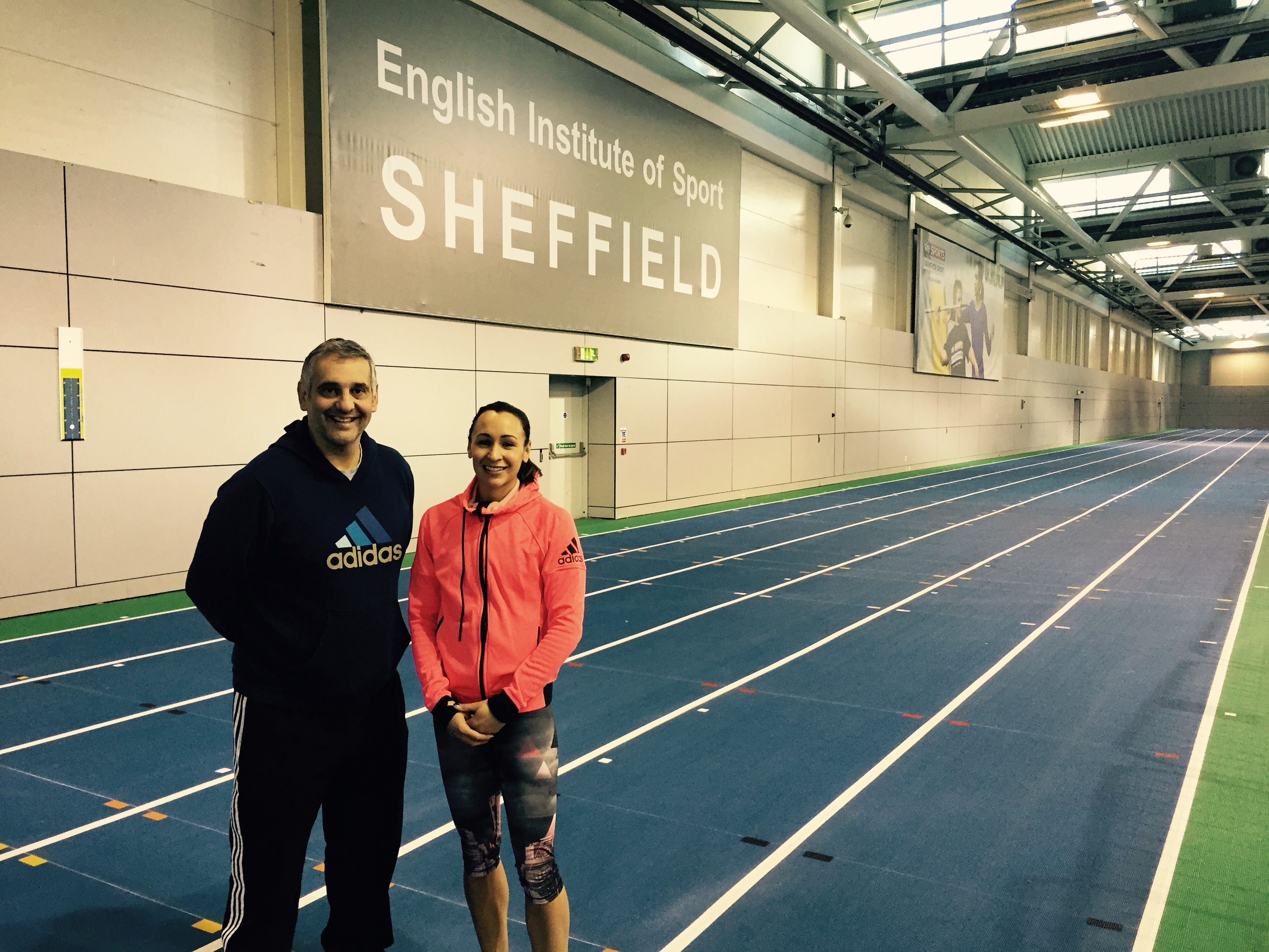 Athlete and coach stood on running track