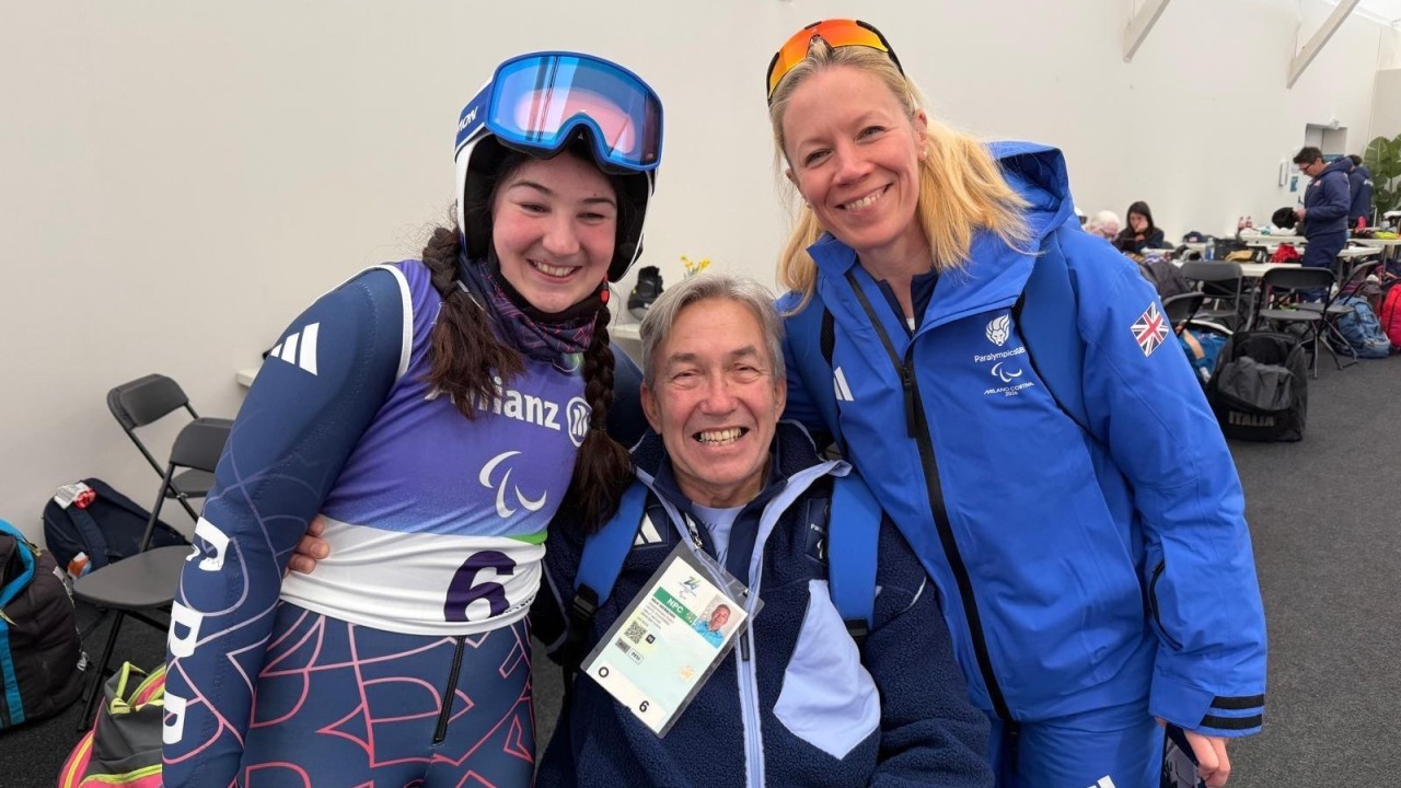ParalympicsGB athlete with support staff posing indoors after competition