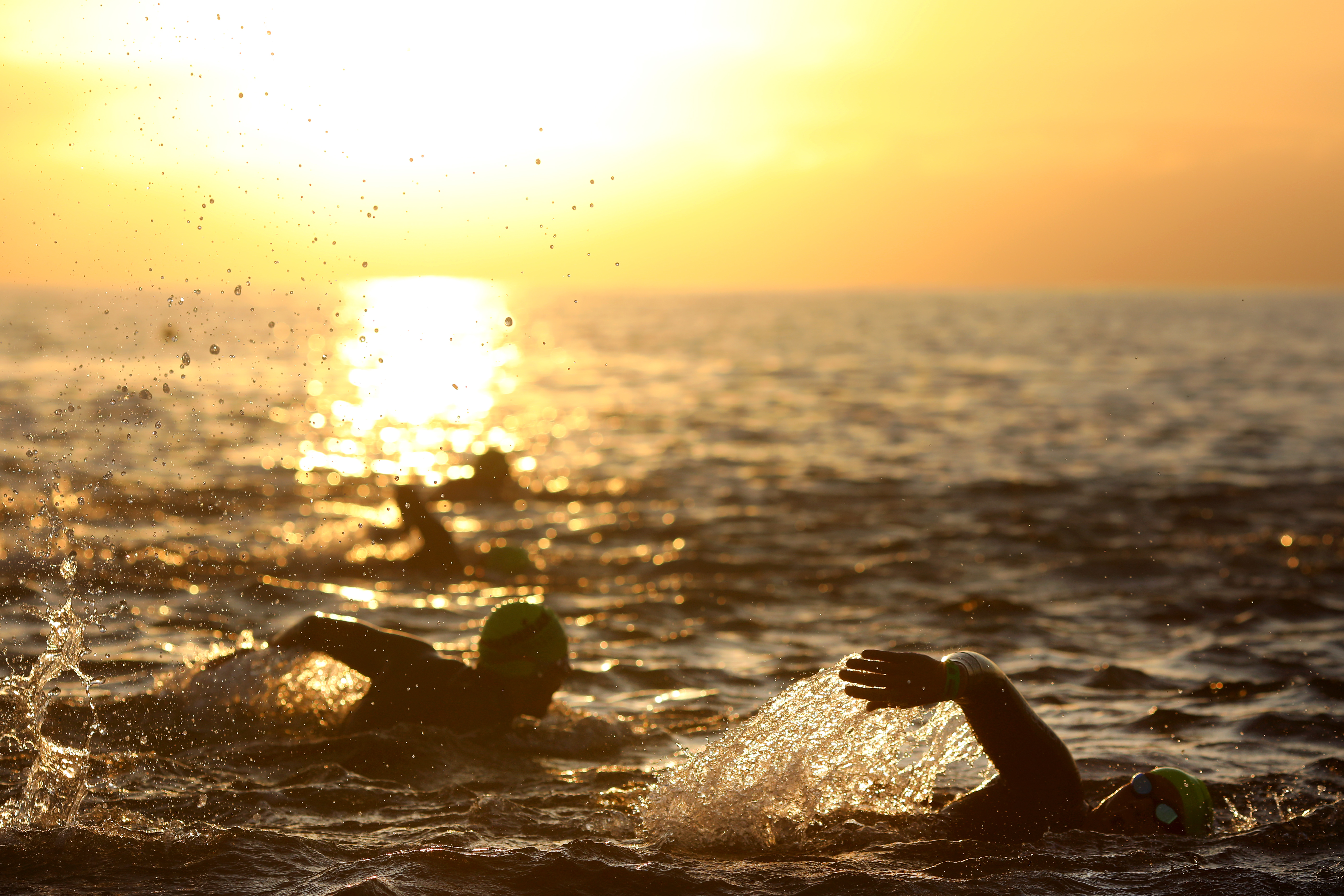 sunrise whilst swimmers swim in the sea on the coast of Britian 