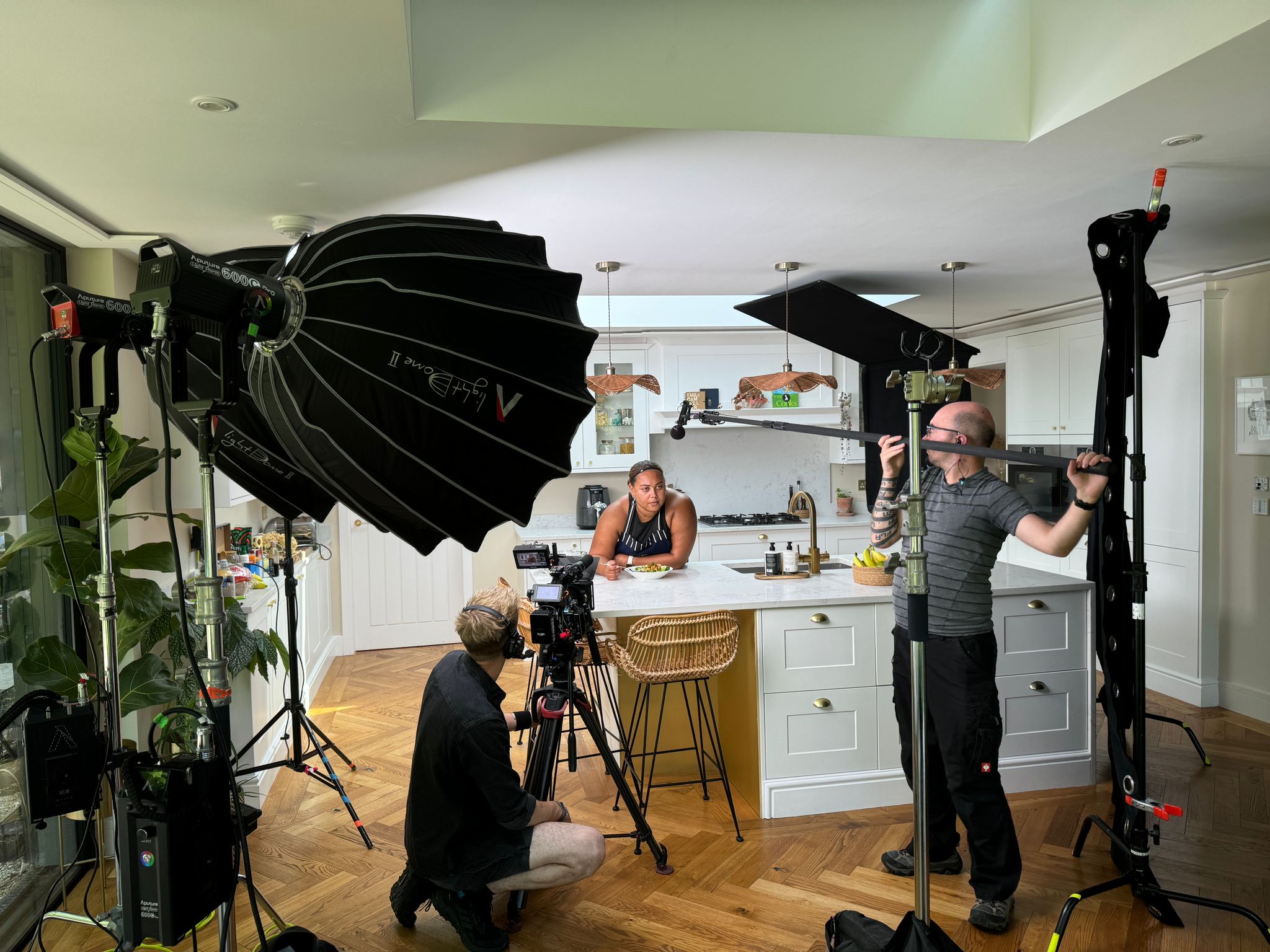 Emily Campbell stood in a kitchen studio with a camera and sound crew member filming her