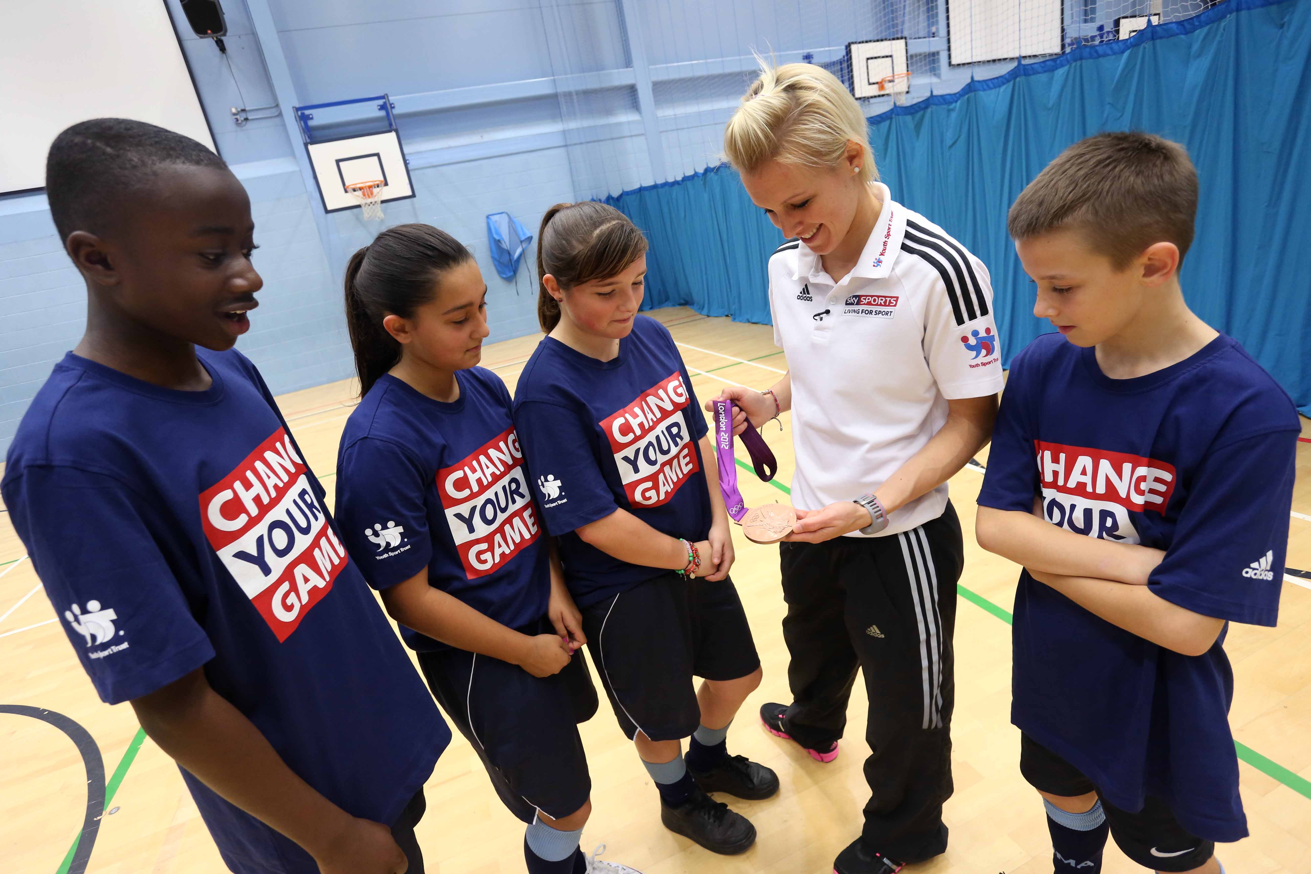 A group of young people being shown a medal by an athlete