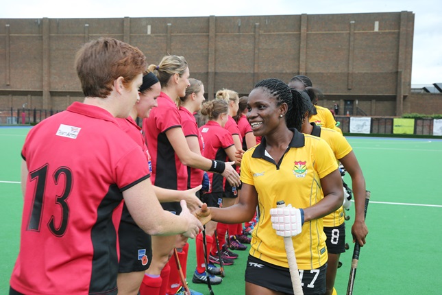 Two hockey teams. One dressed in red and one dressed in yellow. Shaking hands before a match.