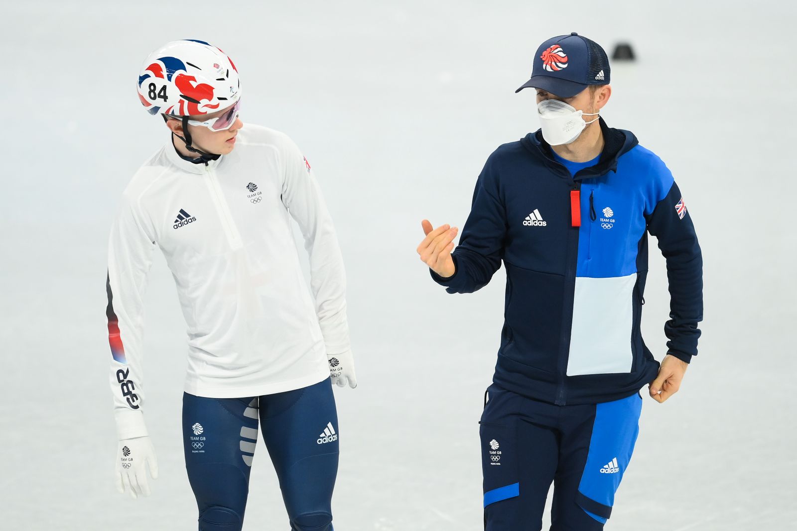 Two people ice skating along and talking. Wearing Team GB kit in preparation for an event at the Olympic Games.