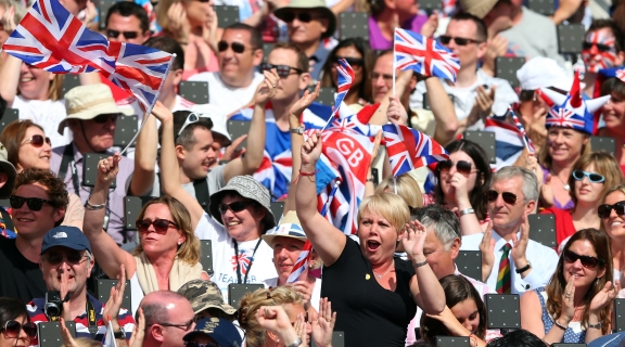 A crowd of cheering sports fans waving Union Jack flags