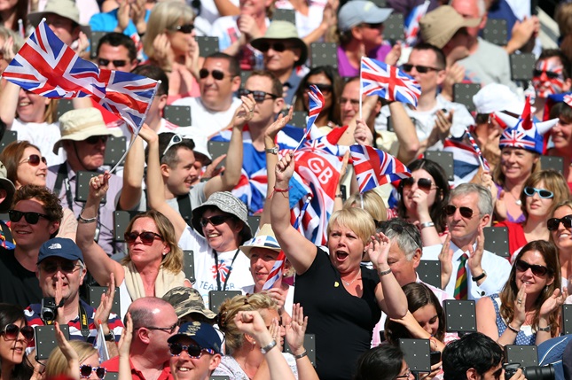 A crowd of cheering sports fans waving Union Jack flags