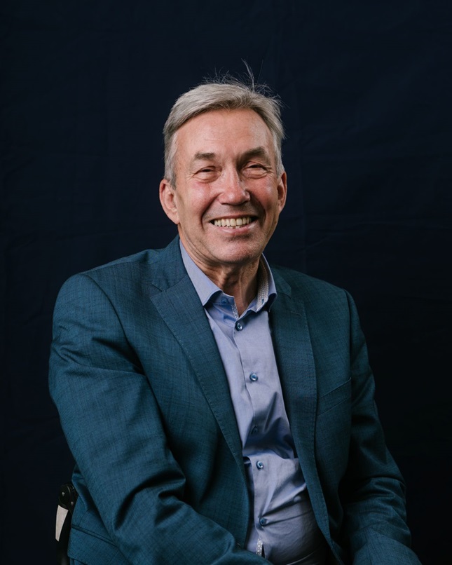 A portrait picture of Nick Webborn, UK Sport Chair, he smiles at the camera in a blue suit.