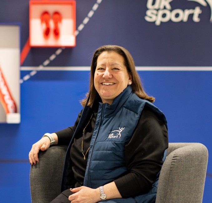 Sally Munday CEO of UK Sport smiling at the camera whilst sat in a chair and smiling at the camera.