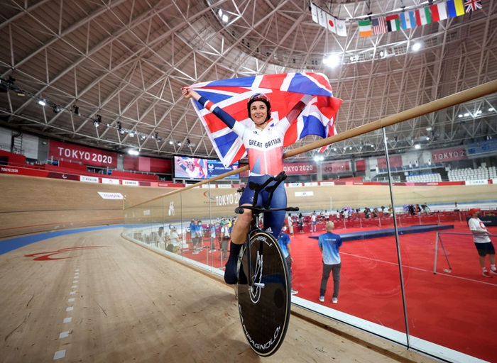 Sarah Storey celebrates holding the GB flag above her head in the Tokyo velodrome