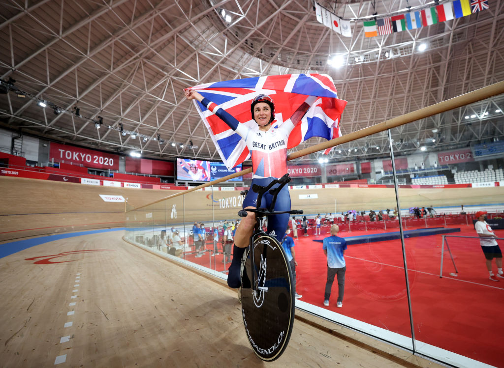 Sarah Storey celebrates holding the GB flag above her head in the Tokyo velodrome