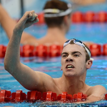 Swimmer in the pool following a race, with raised fist celebrating their performance