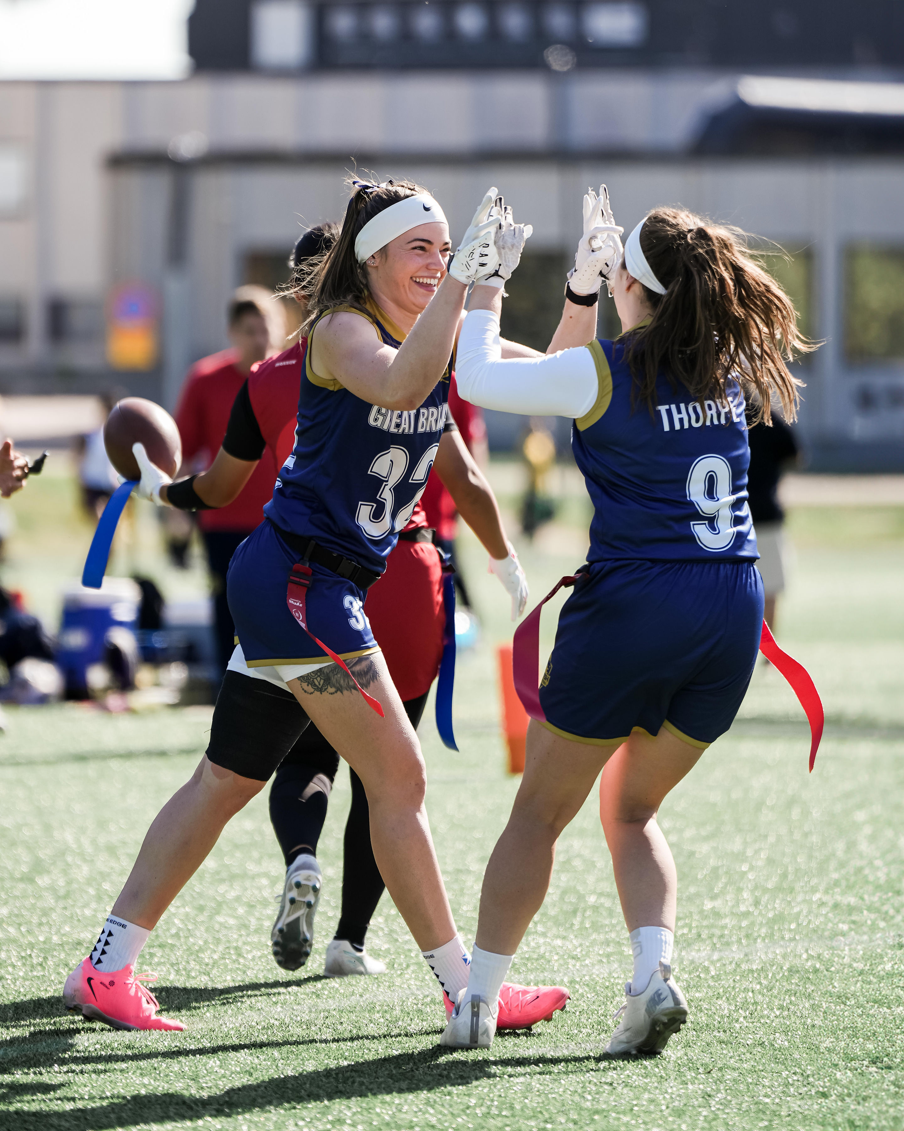 GB women vs Canada in Flag Football, two women high five.
