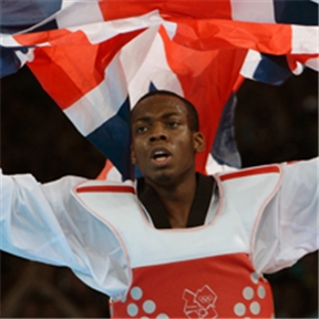 Lutalo Muhammad dressed in taekwondo kit, holding a union jack flag above his head in celebration