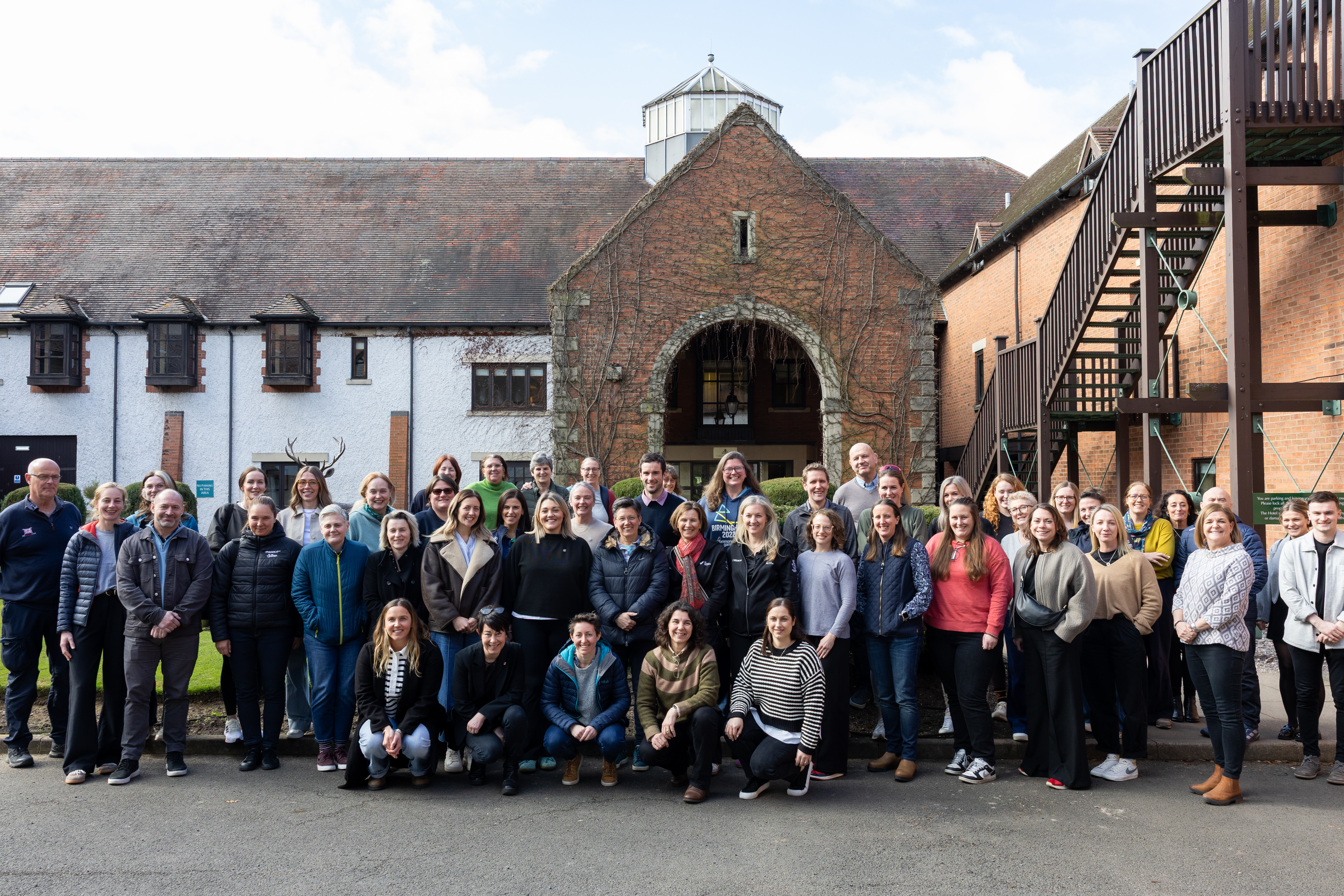The attendees of the Women in Coaching event with standing in front of a building.