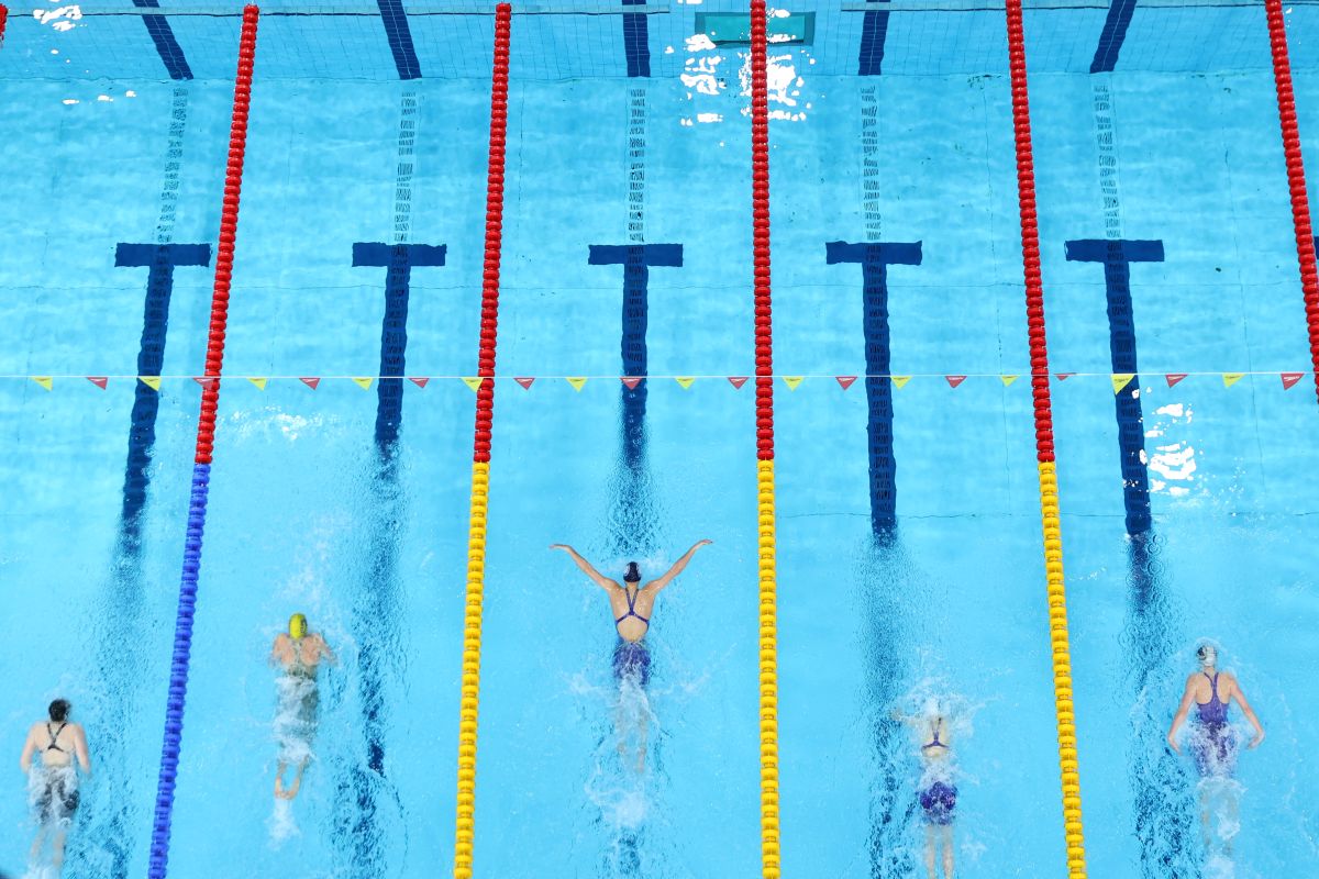 Overhead view of five swimmers racing in separate lanes of a swimming pool.