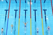 Overhead view of five swimmers racing in separate lanes of a swimming pool.