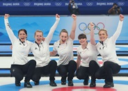 Team GB women's curling team celebrating on the ice after winning gold at the Beijing Winter Olympics 
