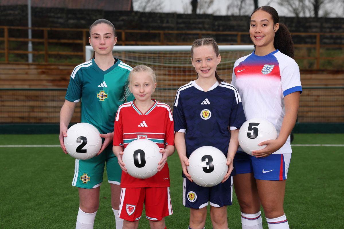 Four players in Northern Ireland, Wales, Scotland and England kits stand on a football pitch holding balls that spell “2035”, promoting the Women’s World Cup 2035 Bid.