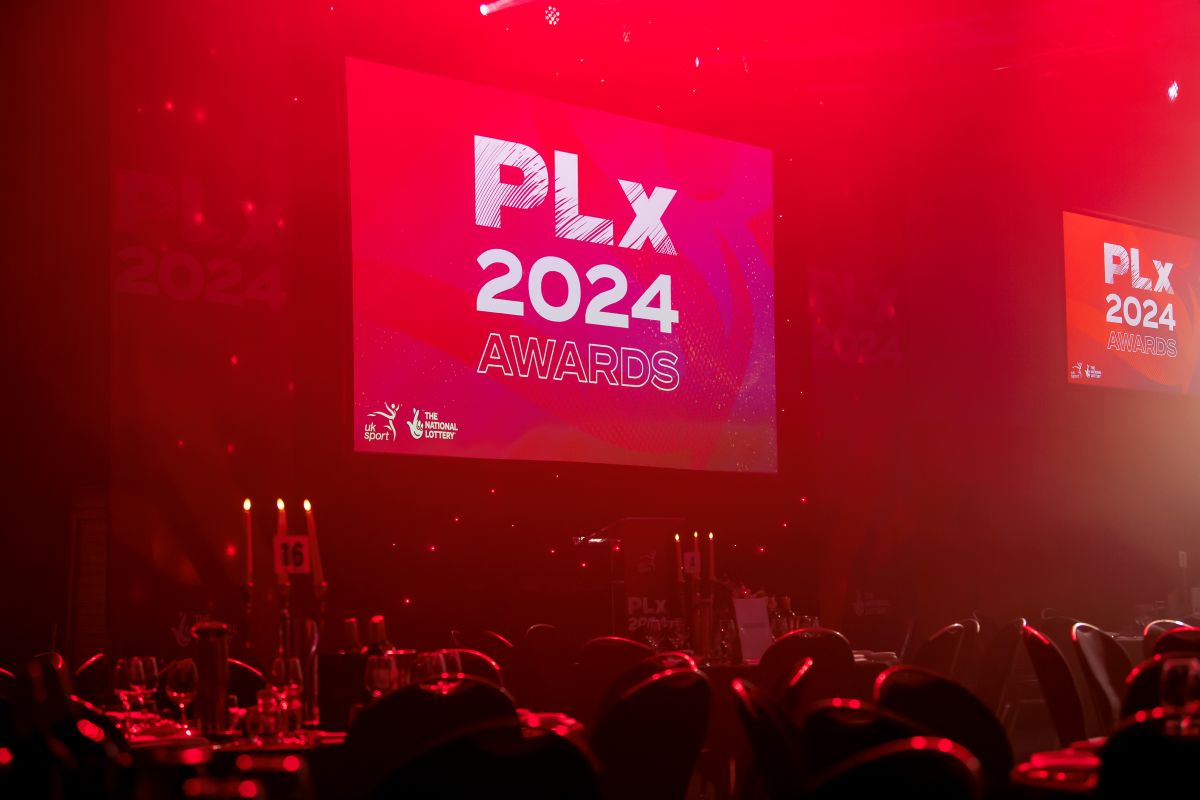 A view of a stage, with red lighting in a dark room - the screen reads PLx 2024 Awards.